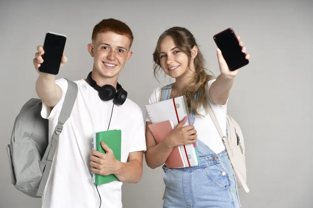 young-students-showing-mobile-phone-to-camera-at-g-2024-11-26-17-52-50-utc